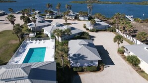 A coastal resort with multiple bungalow-style buildings, a central swimming pool, and a view of the ocean. - Cottage with Boat Dockage, Steps to Private Beach Access! (St. Augustine)