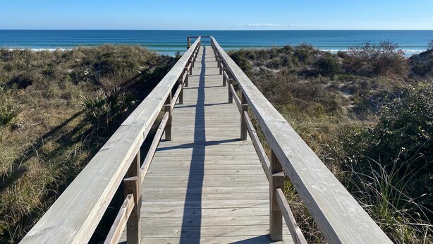 A wooden boardwalk leading to the beach, surrounded by vegetation. - Cottage with Boat Dockage, Steps to Private Beach Access! (St. Augustine)