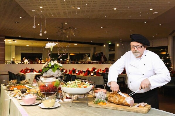 A chef preparing food in a restaurant with a buffet setup. - Herttua Hotel and Spa (Savonlinna)