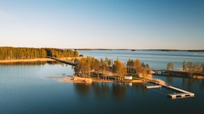 A serene lakeside view with a dock extending into the water, surrounded by dense trees and a clear sky. - Herttua Hotel and Spa (Savonlinna)