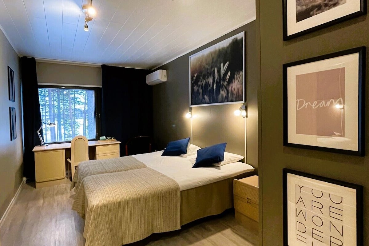 A bedroom with two beds, a desk, and a window.