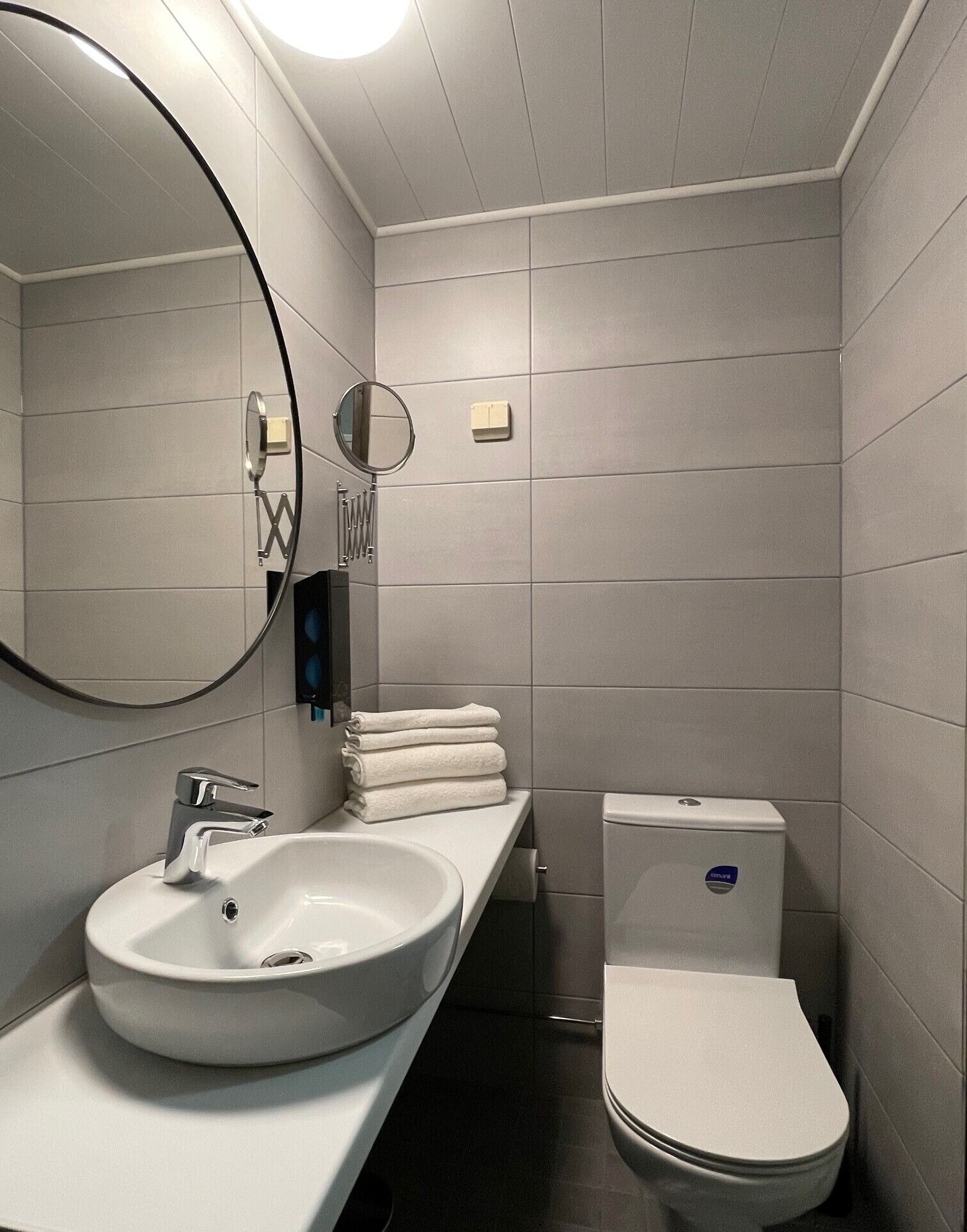 A modern bathroom with a white sink, mirror, and toilet.