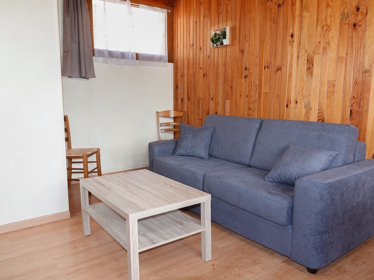 A room with a blue sofa, a wooden coffee table, and a wooden chair.