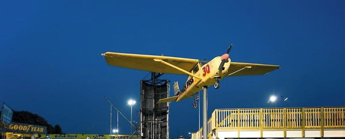 A nighttime scene with go-karts and a yellow airplane.