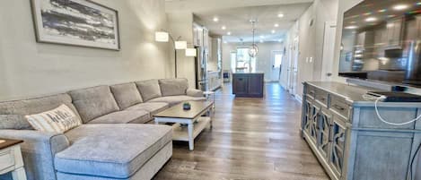 A spacious living room with a grey sectional sofa, a coffee table, and a TV cabinet.