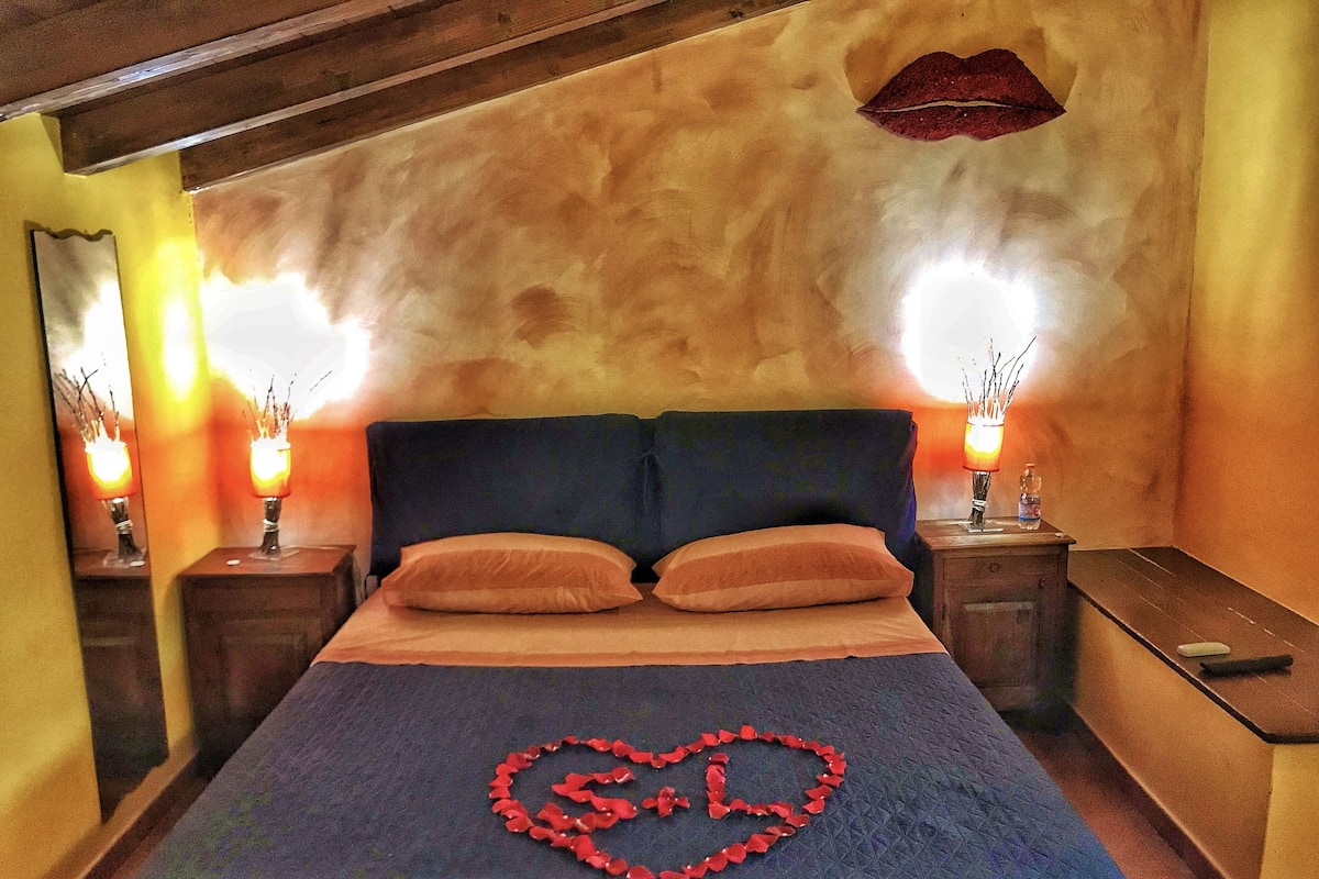 A bedroom with a bed, two nightstands, a wall-mounted lamp, and a heart-shaped decoration on the bed.