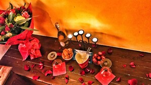 Una mesa de madera con una botella de champán, un candelabro y un bol de pasteles.