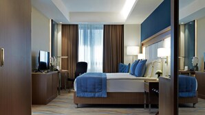 Una habitación de hotel moderna con una cama grande, un escritorio, una silla y un espejo.