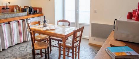 A kitchen with a wooden table and chairs, a hanging light fixture, and a window with a view.