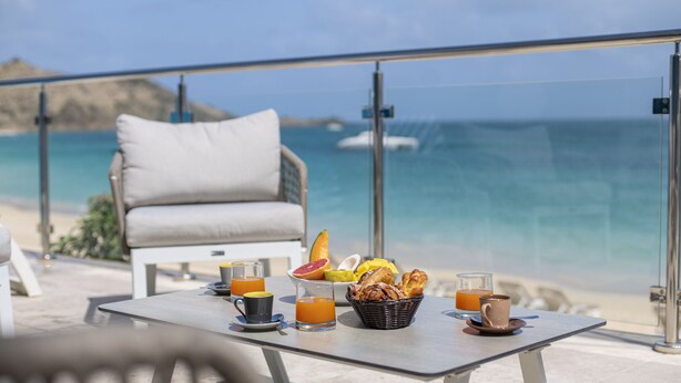 A table with breakfast items and a view of the ocean. - Magnificent waterfront apartment (Grand-Case)