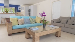 A living room with a blue sofa, a grey sofa, and a glass coffee table. - Magnificent waterfront apartment (Grand-Case)