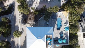 Vue aérienne d’une propriété résidentielle dotée d’une piscine, d’un espace salon extérieur et d’un patio couvert.