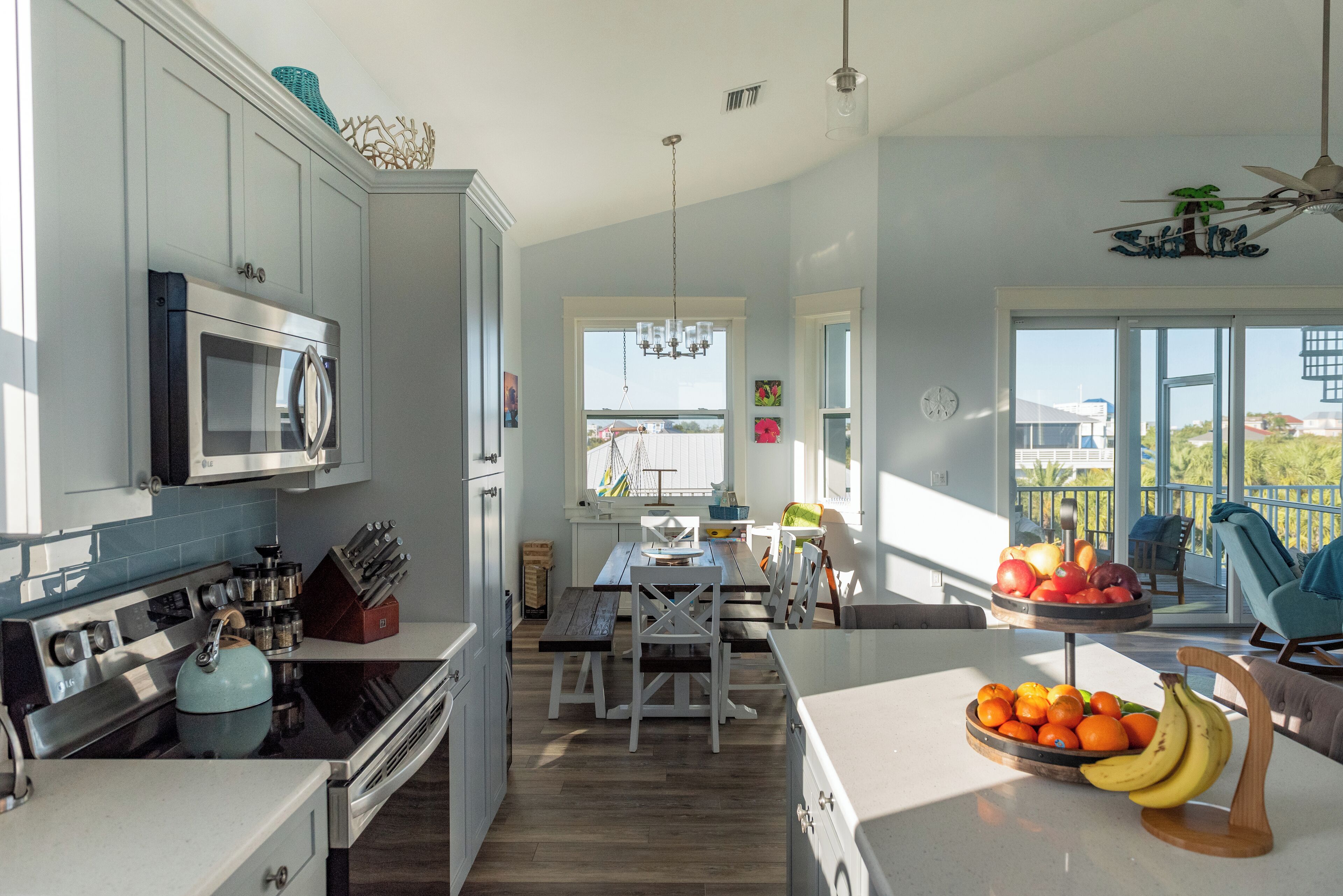 A modern kitchen with a dining area, a view of the outside, and a balcony with outdoor seating.