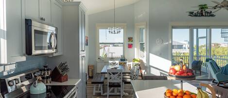 A modern kitchen with a dining area, a view of the outside, and a balcony with outdoor seating.