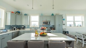 Une cuisine moderne avec des meubles de couleur bleu clair, un îlot central doté de sièges et divers appareils électroménagers.