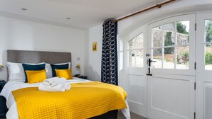 A bedroom with a bed, a nightstand, a bedside table, a window, and a door.