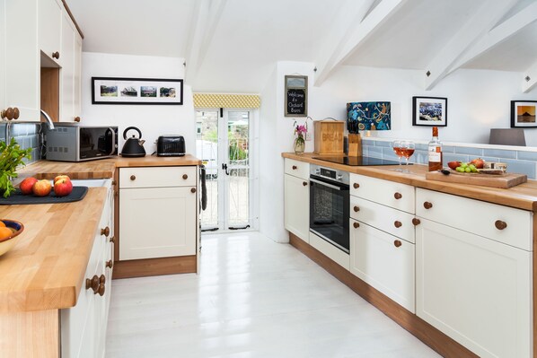 A modern kitchen with white cabinetry, a wooden countertop, and a view to the outside. - Idyllic Cornish converted barn 10 mis to St Ives & beaches (St Erth, Hayle)