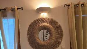 Ett rum med en rund spegel, ett litet bord och en pall.
