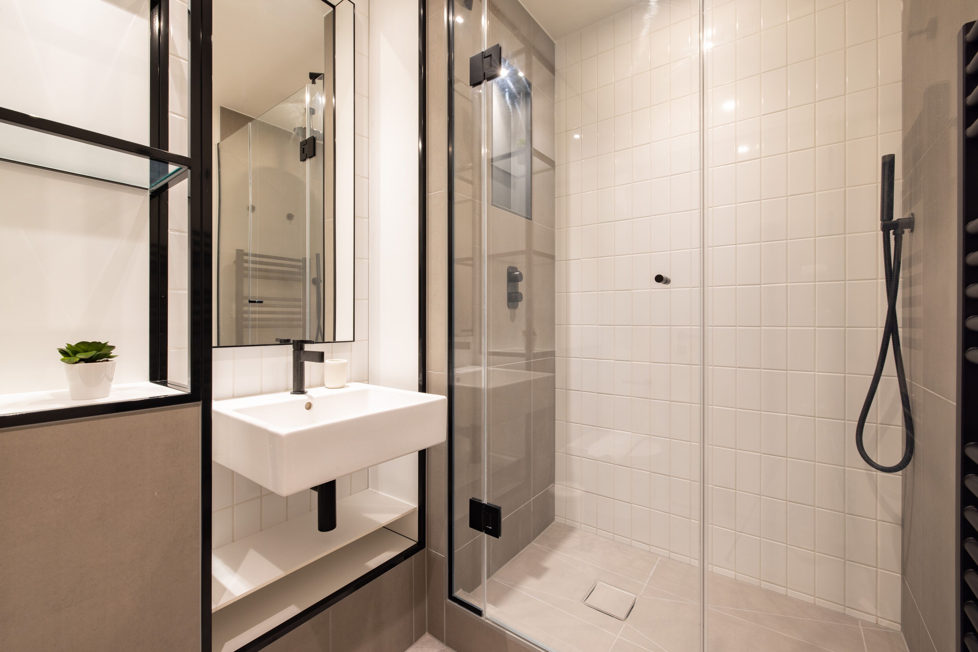 A modern bathroom with a glass-enclosed shower, a white sink, and a mirror.