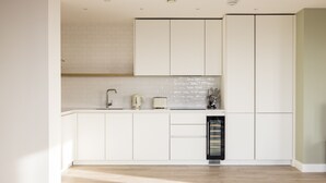 A modern kitchen with white cabinetry, a tiled backsplash, and a built-in oven. - The Wembley Apartment (Wembley)