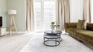 A modern living room with a sofa, a coffee table, and a lamp. - The Wembley Apartment (Wembley)