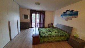 A bedroom with a bed, a dresser, a chair, a desk, and a window with curtains.