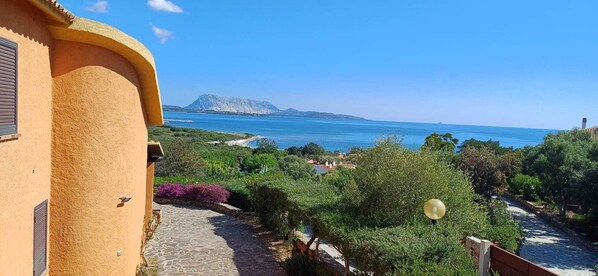 Une vue sur la côte, avec un sentier en pierre menant à un bâtiment à la façade jaune.