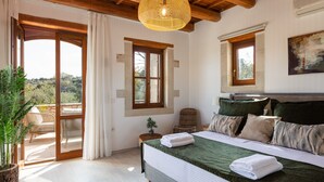 A bedroom with a large bed, a wooden ceiling, a window, and a view of the outdoors.