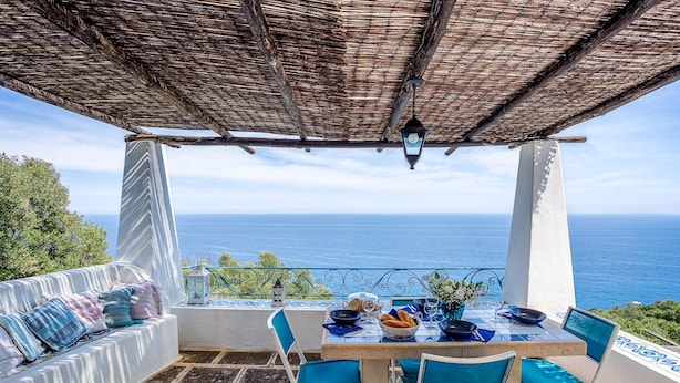 Eine Terrasse mit Esstisch, mit Blick auf das Meer.