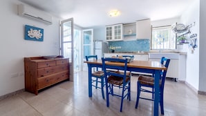 Eine kompakte Küche mit Essbereich, ausgestattet mit einem Holztisch und blauen Stühlen, einem weißen Schrank und einem Fenster mit Aussicht.