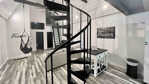Een modern interieur met een spiltrap, een hangstoel, een klein tafeltje en een bord aan de muur.