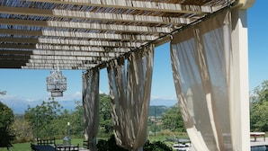 A covered outdoor seating area with wicker furniture and a view of the landscape. - THERESA SULLA COLLINA (Passerano Marmorito)