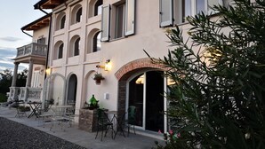 A two-story building with a balcony, outdoor seating, and a brick archway. - THERESA SULLA COLLINA (Passerano Marmorito)
