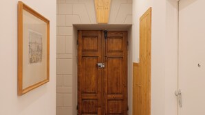 Un pasillo con puertas dobles de madera, un cuadro enmarcado a la izquierda y un letrero encima de las puertas.
