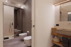 A modern bathroom with a bathtub, toilet, and sink. - San Nicolò Suites (Trieste)