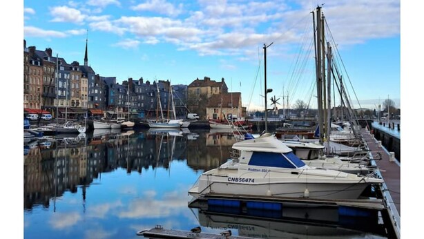 A marina with boats docked, a building with a tower, and a clear sky. - forest house (Le Theil-en-Auge)