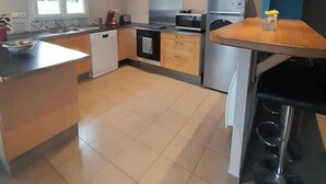 A modern kitchen with a central island, built-in oven, microwave, and a stove. - forest house (Le Theil-en-Auge)