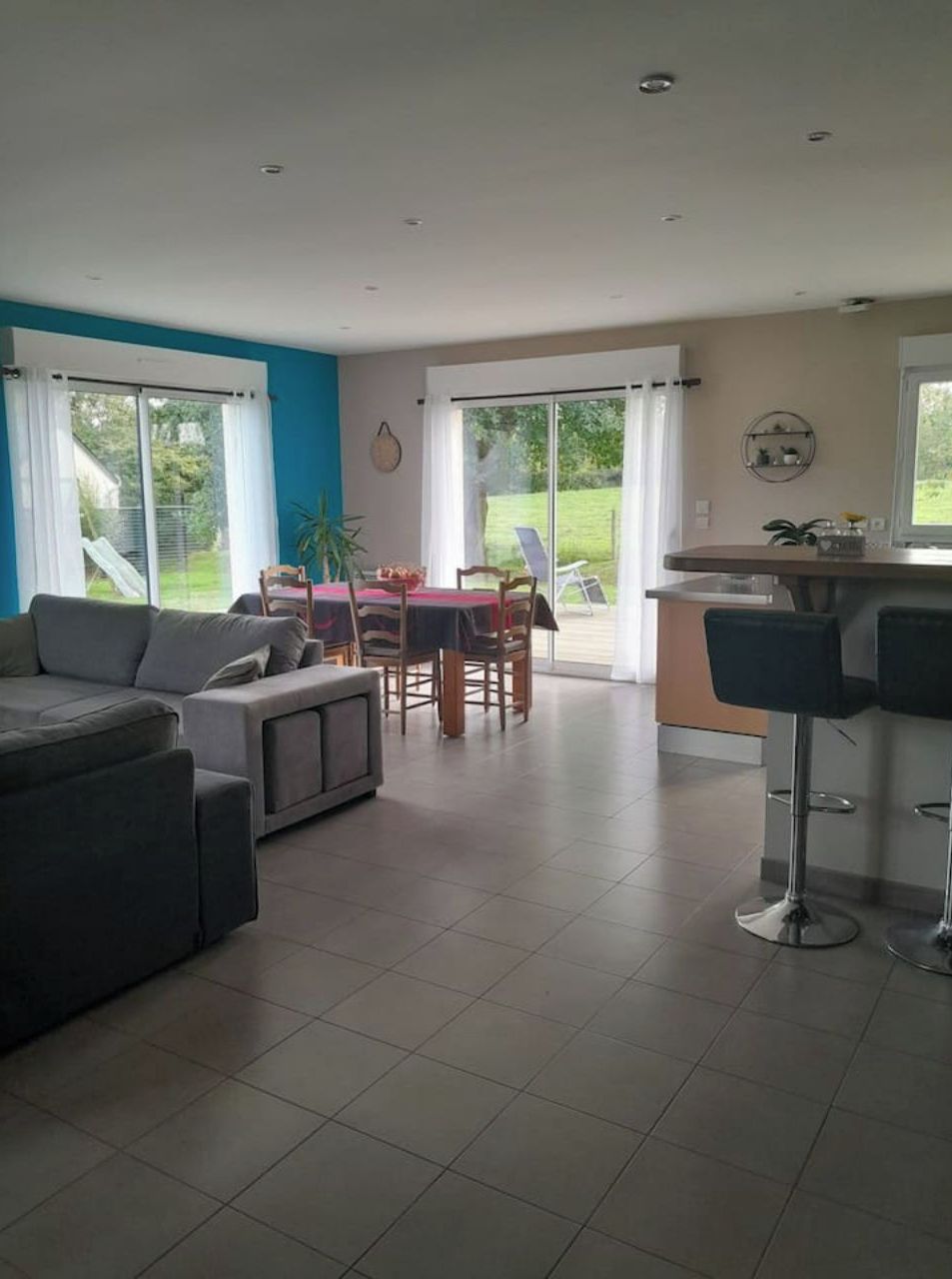 Uma sala de estar moderna com um sofá, uma mesa de jantar com cadeiras e uma área de cozinha com balcão.