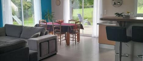 Una sala de estar moderna con un sofá, una mesa de comedor con sillas y una zona de cocina con barra.