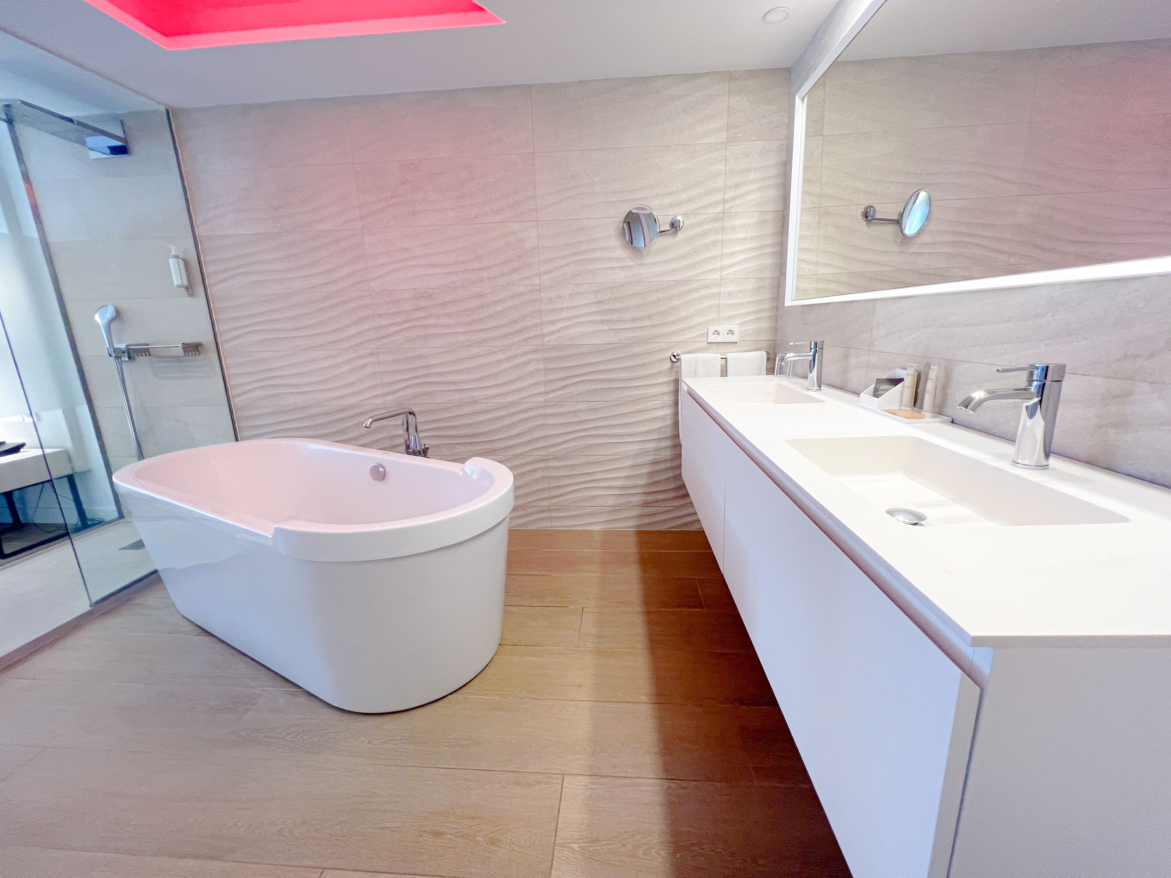 Ein modernes Badezimmer mit einer freistehenden Badewanne, einem großzügigen Waschtisch mit Spiegel und einer Duschkabine.