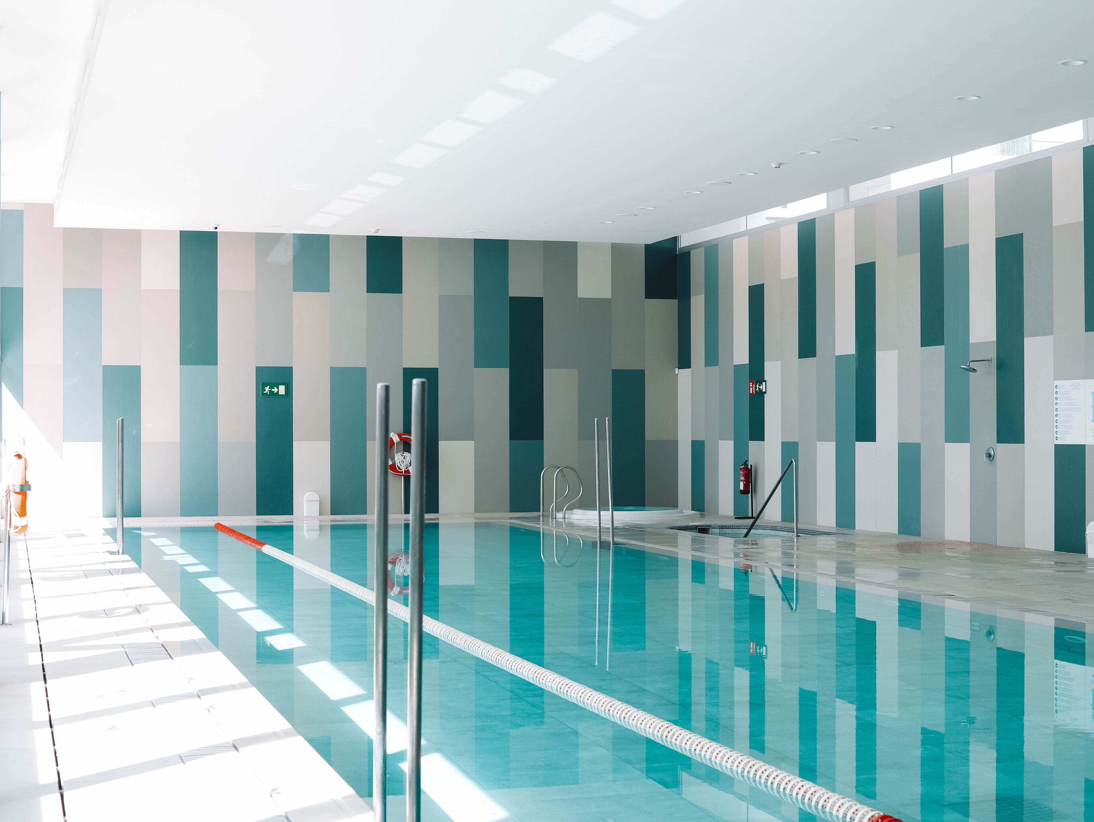 An indoor swimming pool with clear lanes, safety equipment, and a tiled floor.