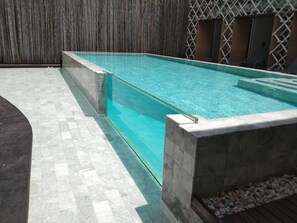 Une piscine rectangulaire à l’eau d’un bleu limpide, entourée d’une terrasse carrelée et d’une clôture en bois.