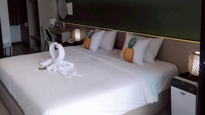 A hotel room with a large bed, a bedside table, a lamp, and an air conditioning unit. - Yanud Residence (Ratsada)