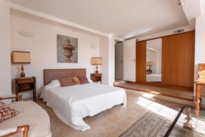 A spacious bedroom with a large bed, a wooden wardrobe, a nightstand, and a chair. - Charming Villa,  Sea View,  minutes from Palm Beach and Cannes (Vallauris)