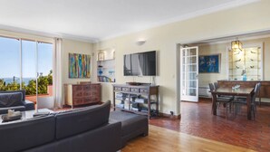 Amplia sala de estar con un sofá grande, un televisor de pantalla plana y una mesa de comedor con sillas.