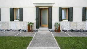 A building with a central entrance, flanked by two potted plants, and a stone pathway leading to the entrance. - Bed and Breakfast Canalgrande (Mira)