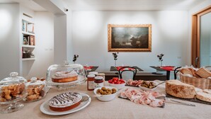 A dining table with various food items and a painting on the wall. - Bed and Breakfast Canalgrande (Mira)