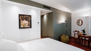 A modern hotel room with a bed, a framed picture, a desk with a chair, a small table with a potted plant, and a mirror on the wall. - Bed and Breakfast Canalgrande (Mira)