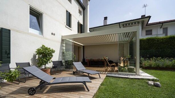 A modern outdoor patio with two lounge chairs, a glass enclosure, and a well-maintained lawn. - Bed and Breakfast Canalgrande (Mira)