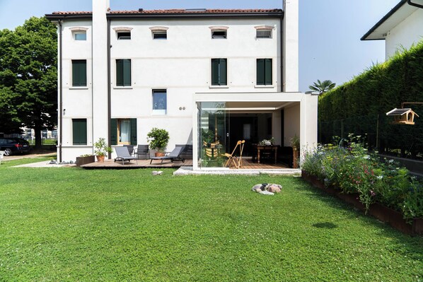 A modern two-story building with a flat roof, a glass entrance, and a well-maintained lawn with outdoor furniture. - Bed and Breakfast Canalgrande (Mira)